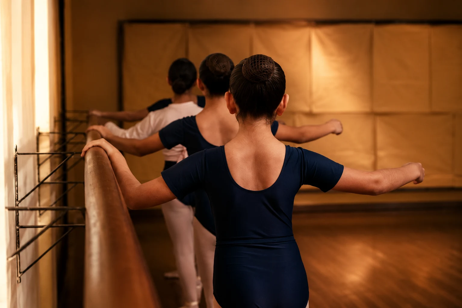 Bailarina adolescente en arabesque en un estudio oscuro